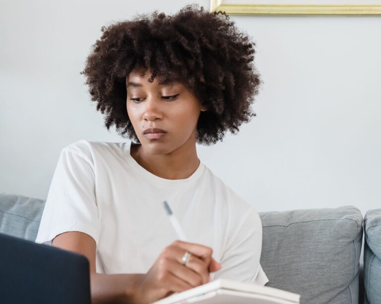 Woman studying at home with a laptop and notebook