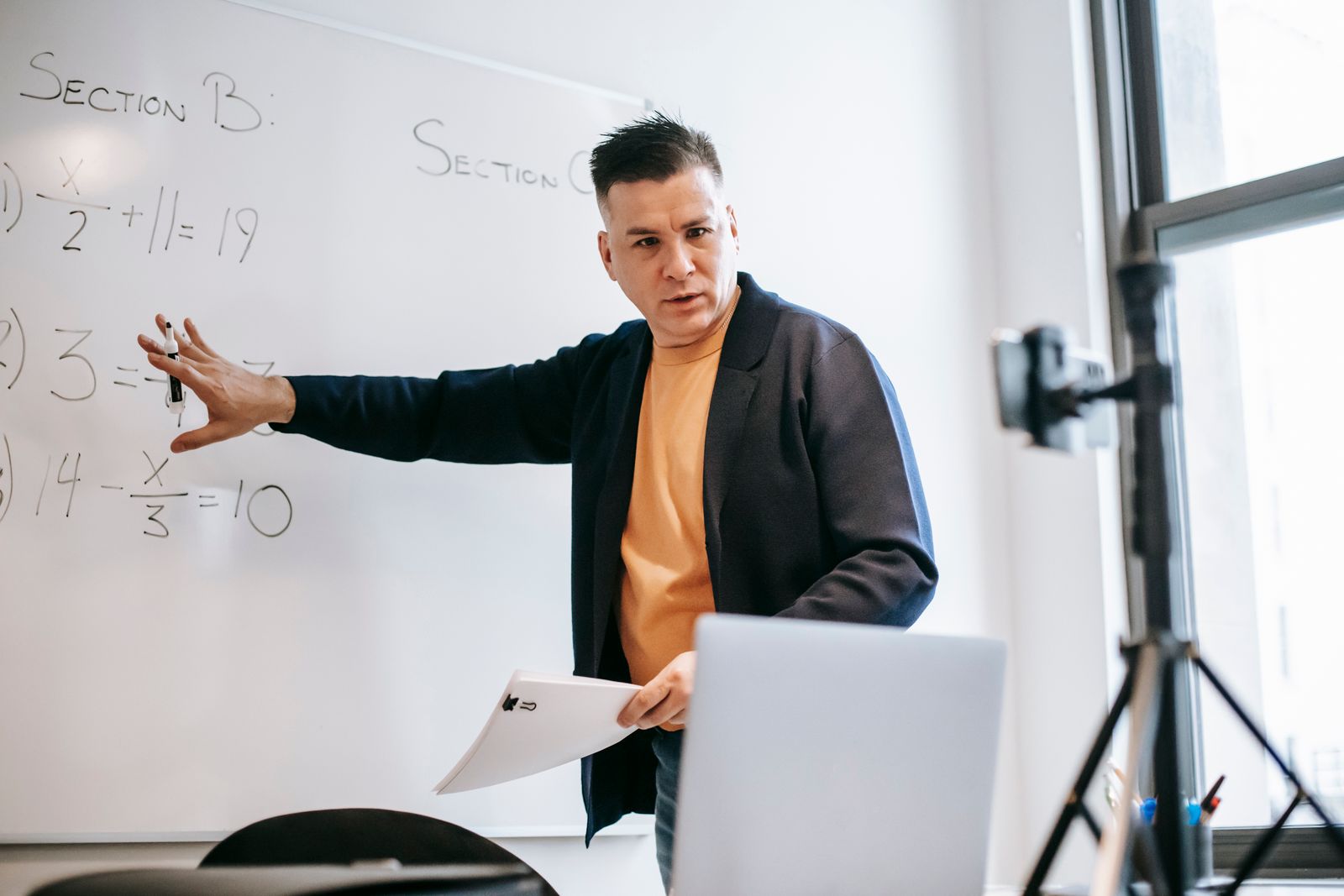 Instructor presenting online with a laptop and whiteboard