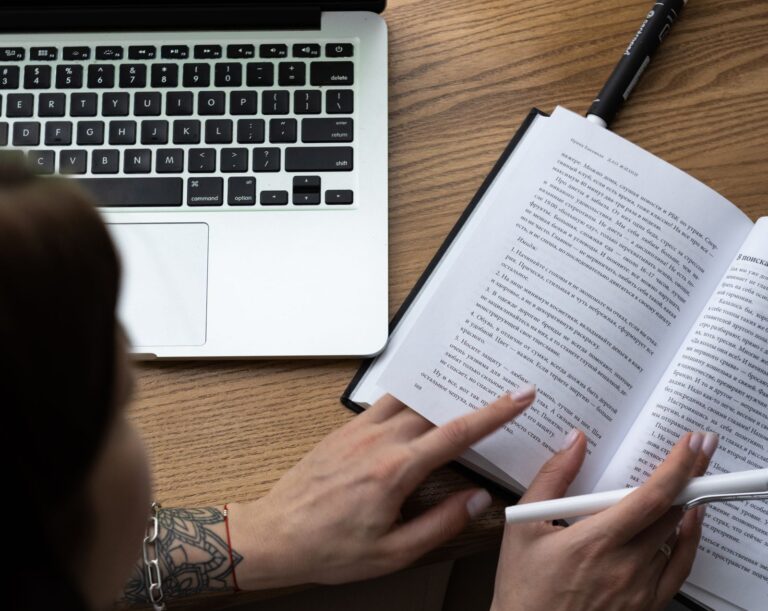 Studying from a textbook beside a laptop